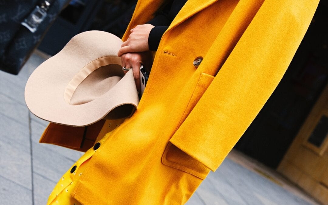 Woman wearing a yellow coat holding a hat
