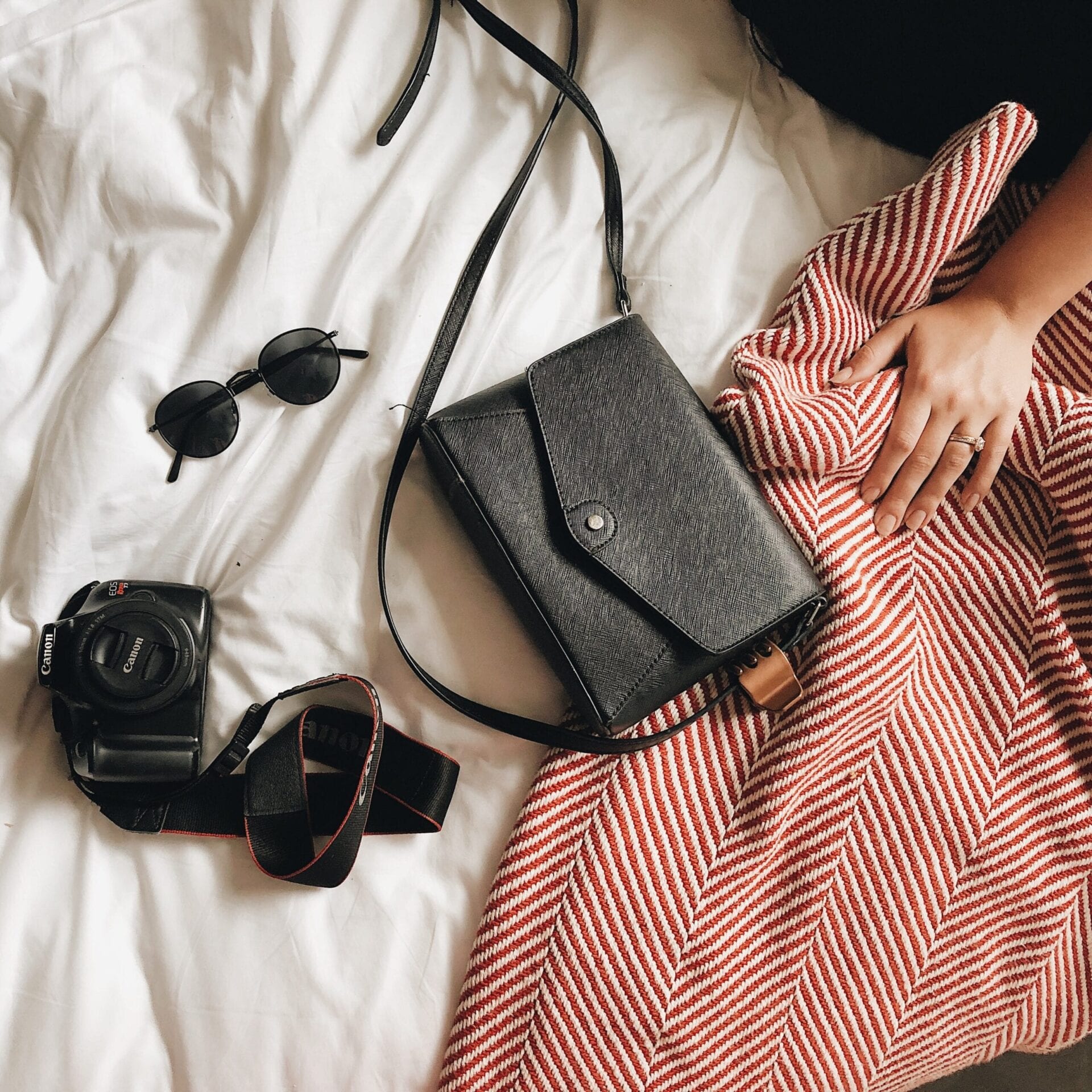 Black purse with accessories on a blanket